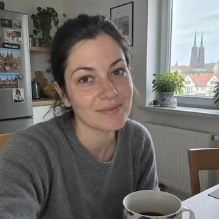 Portret Oly Kubiakiej, kobiety po trzydziestce z ciemnymi włosami w szarym swetrze